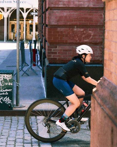 Woman cycling in the Women's EdW Edition Jersey, showcasing style and functionality on a city street.